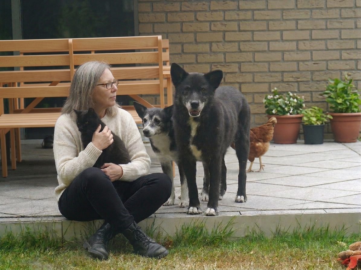 Petra Pistorius mit ihren geretteten Tieren: einer Katze, zwei schwarzen Hunden und einem Huhn